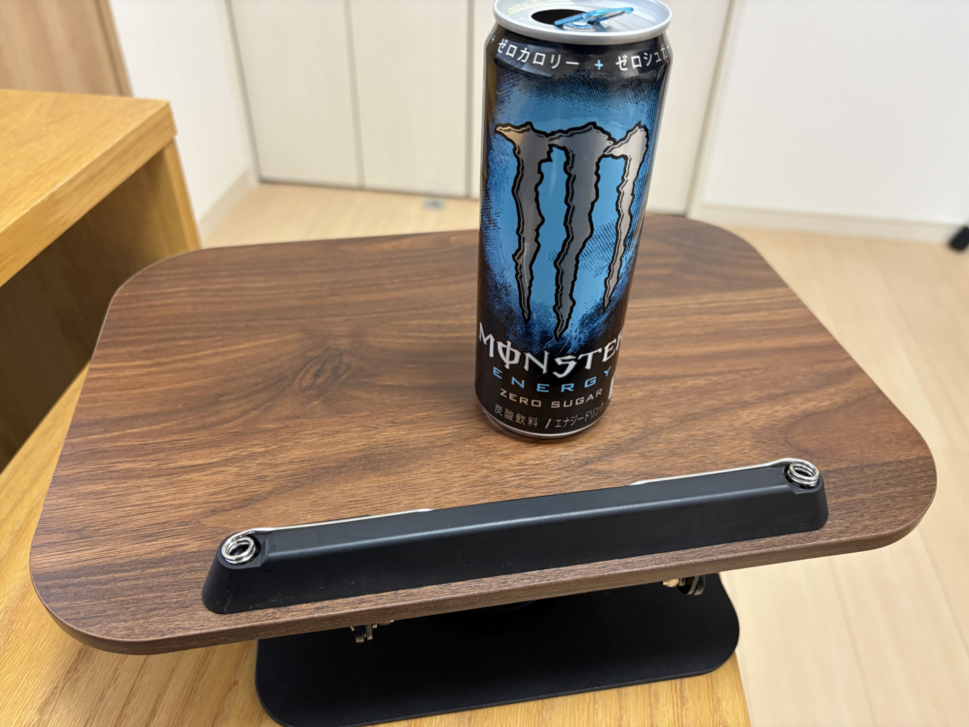 板を平らにしたブックスタンドに、飲み物の缶を置いた様子